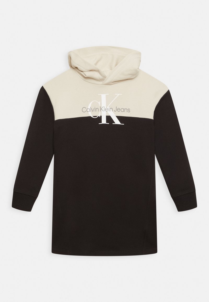 Mikina s kapucí s krémovou horní částí a černým dolním tělem. Obsahuje velké logo "CK" a bílý text "Calvin Klein Jeans".