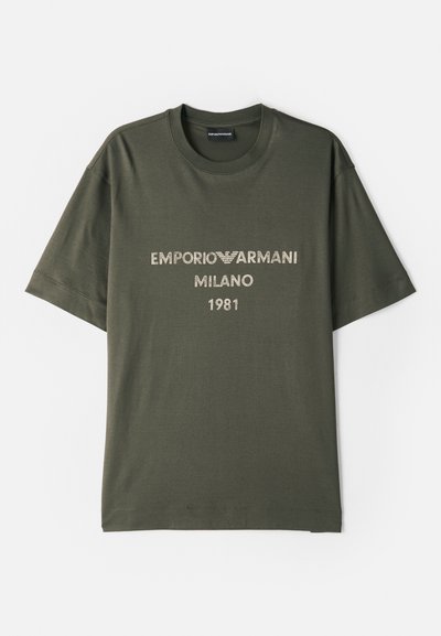 Olivno zeleno bombažno majico s kratkimi rokavi, ki nosi logo "EMPORIO ARMANI MILANO" in "1981" v kontrastni svetli pisavi.