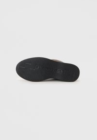 Talpă din cauciuc negru cu un model texturat pentru aderență, având un superior ușor de culoare maro, care oferă durabilitate și confort.