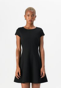 Robe noire à manches courtes avec un col rond, corsage ajusté et jupe évasée. Fabriquée dans un tissu lisse avec des détails de couture subtils.