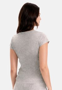 Camiseta gris de manga corta que muestra una vista cercana de una textura suave y lisa y un diseño ajustado, con un escote redondeado y vista desde atrás.