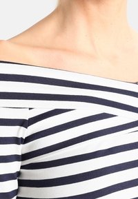 Bluzka bez ramiączek w poziome niebieskie i białe paski, wykonana z lekkiej bawełny, z dopasowanym gorsetem i gładką teksturą.