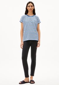 Blue and white striped short-sleeve t-shirt with a round neckline, paired with black skinny jeans and dark slide sandals.