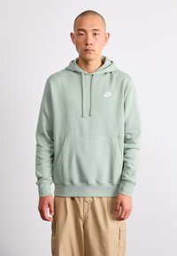 Sweatshirt verde menta feito de um tecido suave, com um bolso frontal, capuz com cordão e um pequeno logotipo branco da Nike no peito.