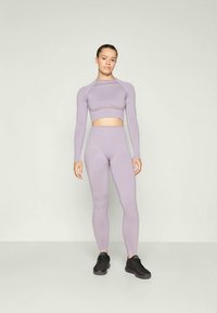 Ensemble de vêtements de sport violet clair comprenant un crop top à manches longues et un legging taille haute. Tissu doux avec une silhouette ajustée et des coutures minimales.