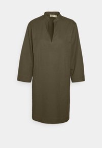 Tunique vert olive à manches longues avec col montant et décolleté en V profond, présentée sur un fond uni.