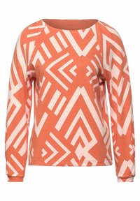 Long-sleeve top in rust orange featuring a geometric white pattern, round neckline, and soft, textured fabric.