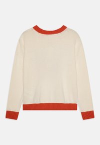 Pull en crème avec un tricot texturé. Présente un col et des poignets côtelés orange contrastants, ainsi qu'une coupe courte avec des épaules tombantes.