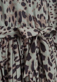 Leopardmuster-Kleid in gedämpftem Grün mit schwarzen und braunen Flecken, mit plissiertem Textur und einem Stoffgürtel in der Taille.