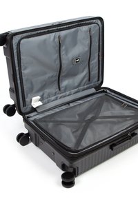 Valise rigide noire ouverte à plat, montrant un intérieur en tissu gris avec des poches zippées, un compartiment en mesh et quatre roues multidirectionnelles.