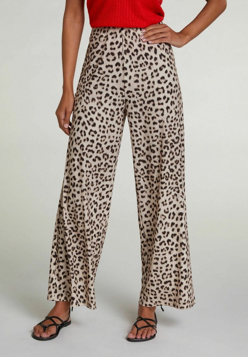 Leopardmønstret bukser i beige med sorte pletter, med en bred ben-design og letvægtsstof, parret med sorte sandaler med stropper.