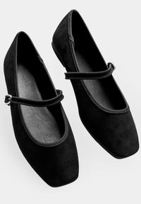 Bailarinas de ante negro con punta cuadrada, que cuentan con una doble correa y una hebilla en tono plata, suela plana y forro interior suave.