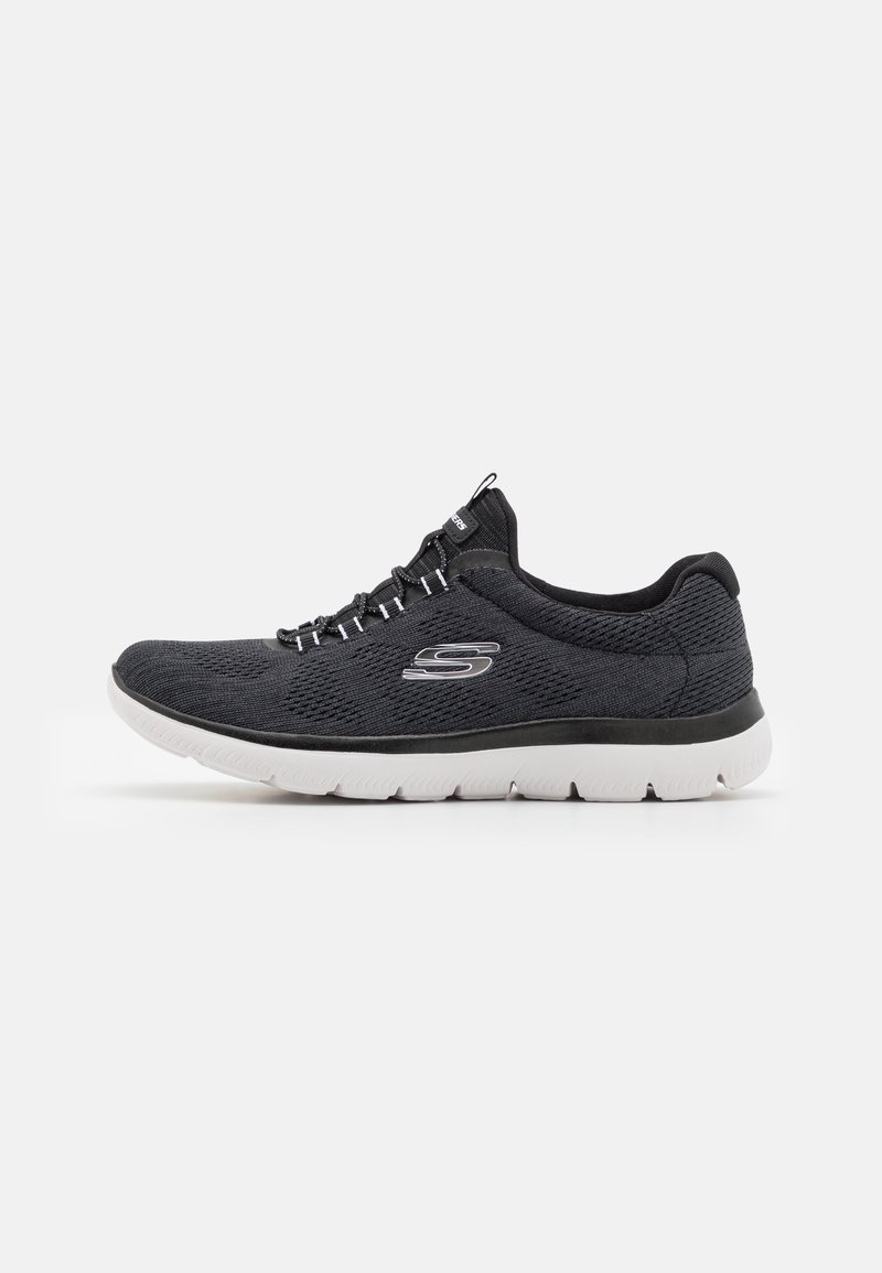 Baskets de sport en tissu noir avec semelles blanches, coupe basse, fermeture lacets et logo « S » sur le côté.