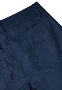 Marinblå byxor med en slät textur, med dubbelsydda sömmar och en enkel bakficka på höger sida.