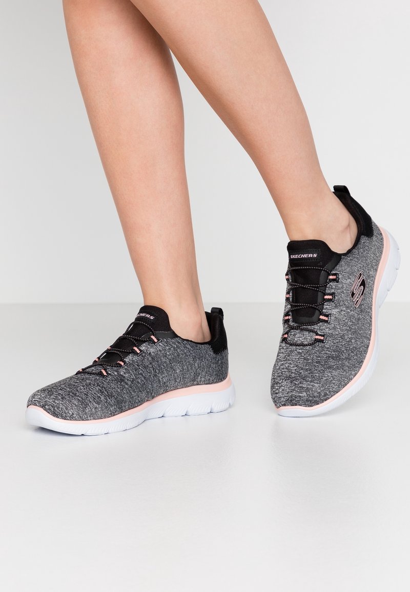 Black and grey athletic shoes with textured knit upper, pink accents, and white rubber sole. Features black laces and a back pull tab.