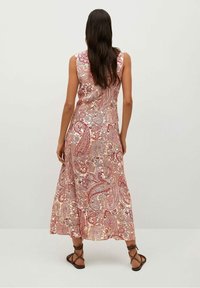 Lang, ærmeløs kjole med et paisley-mønster i røde, pink og cremede farver. Stof har en glat tekstur og en flydende silhuet.