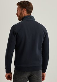 Felpa blu navy con colletto alto, polsini e orlo a coste. Realizzata in un tessuto morbido con dettagli minimi, adatta per un look casual.