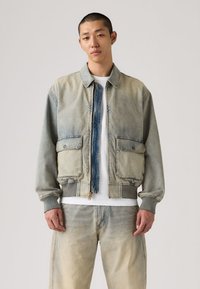 Τζιν μπουφάν με ανοιχτόχρωμο πλύσιμο, κλείσιμο με φερμουάρ μπροστά, δύο τσέπες με πάνελ, και ριμπ μανσέτες. Διαθέτει μπλε κεντρικό πάνελ και ξεθωριασμένη υφή.