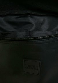 Interno di una borsa di tessuto nero con texture liscia, dotata di chiusura con zip e di un'etichetta in rilievo "URBAN CLASSICS".