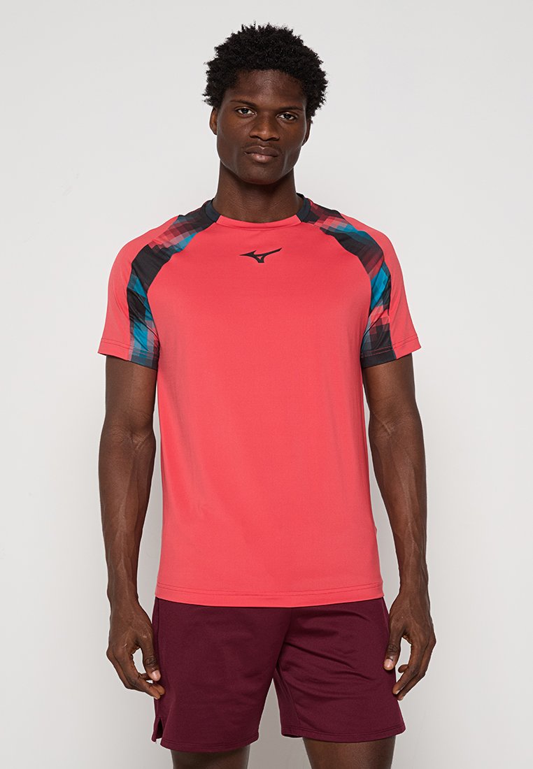 T-shirt de sport rouge avec des accents en noir et bleu à motifs sur les épaules, les manches courtes et un col rond. Conçu pour le sport.