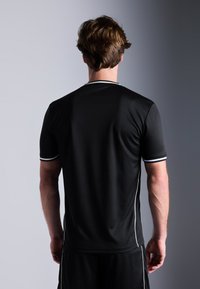 Camiseta atlética negra hecha de tela texturada, con mangas cortas, un escote redondo y detalles en blanco a lo largo del cuello y las mangas.