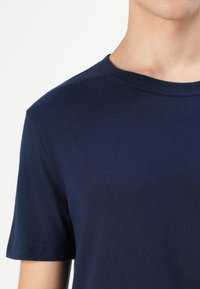 T-shirt en coton bleu marine avec un col rond classique et des manches courtes, présentant une texture lisse et sans motifs ni accents visibles.