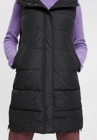 Czarna puchowa kamizelka z zamkiem błyskawicznym z przodu i zatrzaskami, wyposażona w kaptur i boczne kieszenie, wykonana z pikowanego, ocieplanego materiału.