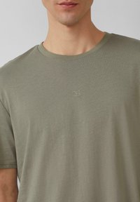 Olijfgroen katoenen T-shirt met korte mouwen, een ronde halslijn en een subtiel geborduurd "QS" logo in bijpassende kleur op de borst.