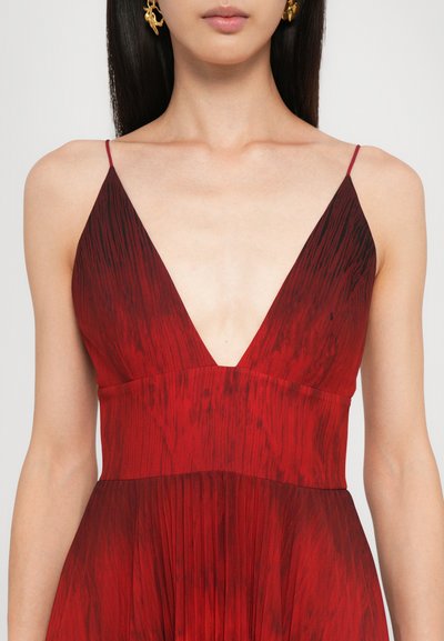 Robe sans manches rouge avec un décolleté en V profond, présentant un design texturé et plissé. Le tissu possède un motif dégradé avec des accents plus foncés en haut.