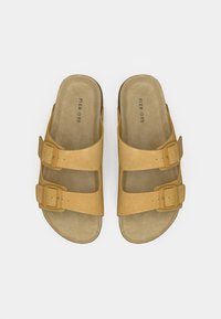 Δερμάτινα σανδάλια ταμπά με δύο ρυθμιζόμενες αγκράφες, επίπεδη σόλα και μαλακό, υφασμένο πέλμα. Μινιμαλιστικός σχεδιασμός, ανοιχτό σχέδιο δακτύλων.