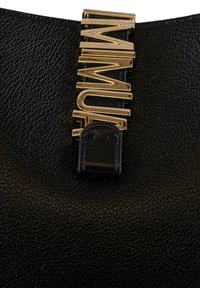 Borsa in pelle nera con superficie texturizzata e una tracolla in metallo dorato con logo. La tracolla presenta dettagli con lettere orizzontali e verticali.