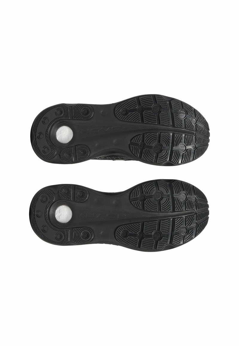 Czarne sportowe podeszwy butów z teksturowanym gumowym wzorem dla lepszej przyczepności, z okrągłymi akcentami i gładką centralną częścią.