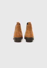 Bottines en suède marron avec un petit talon empilé, dotées de pattes de tirage à l'arrière et d'une doublure intérieure lisse.