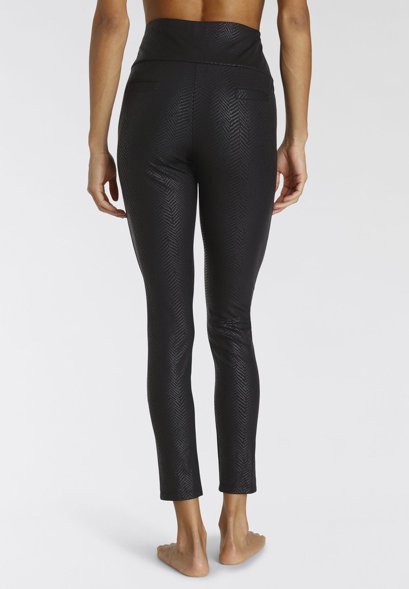 Leggings neri caratterizzati da un motivo a spina di pesce e una vita alta con due tasche posteriori. Il materiale ha una leggera lucentezza ed è aderente.
