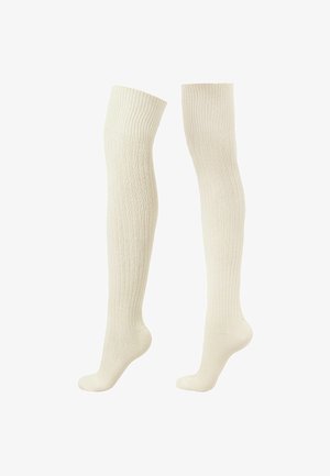 Calcetines crema hasta la rodilla, hechos de material de punto con acanalado vertical y talones reforzados, que presentan una textura suave y puños elásticos.