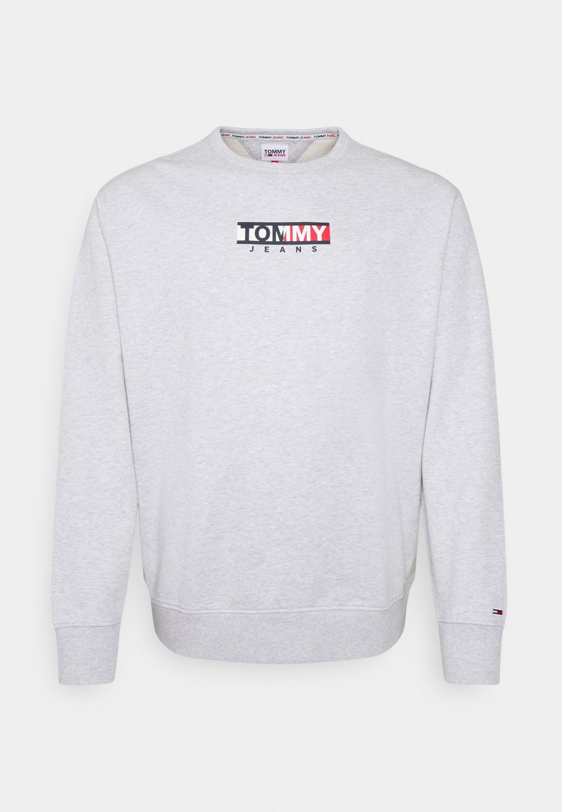 Lysegrå langærmet sweatshirt med ribstrikkede manchetter og kant, med "Tommy Jeans" logo i sort, hvid og rød på brystet og et lille flag på ærmet.