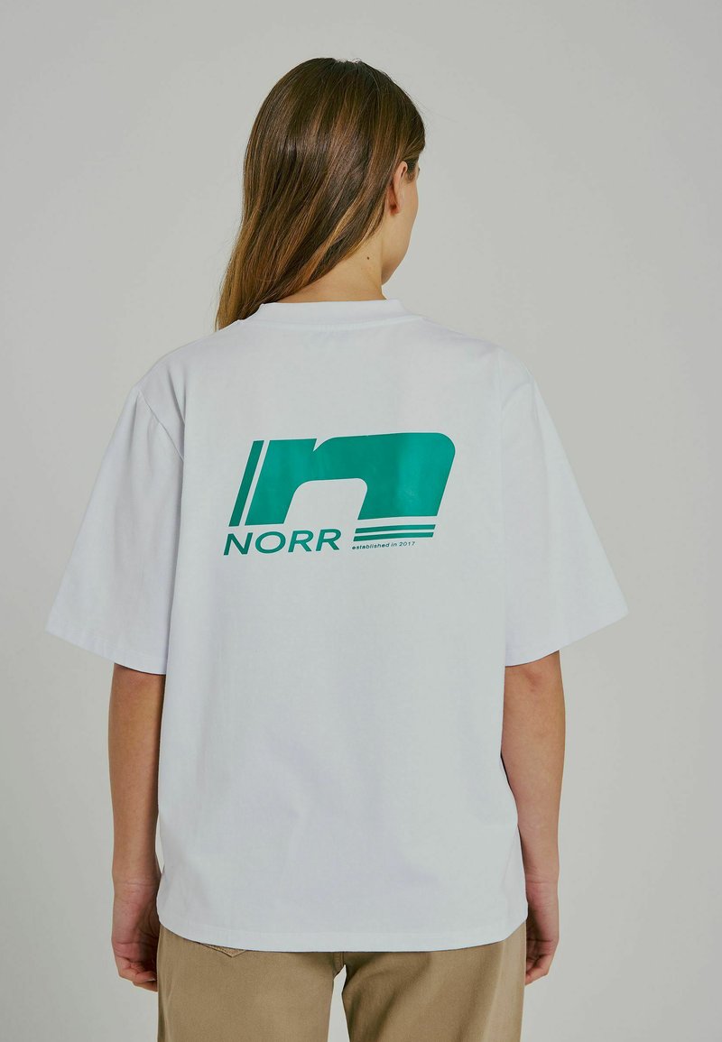Vit oversized T-shirt gjord av bomullsmix, med en teal grafisk design som har "NORR" och "grundad 2017" på baksidan.