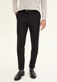 Black tailored trousers with a smooth texture, featuring a slim fit, cuffed hems, and a front button closure for a polished look.