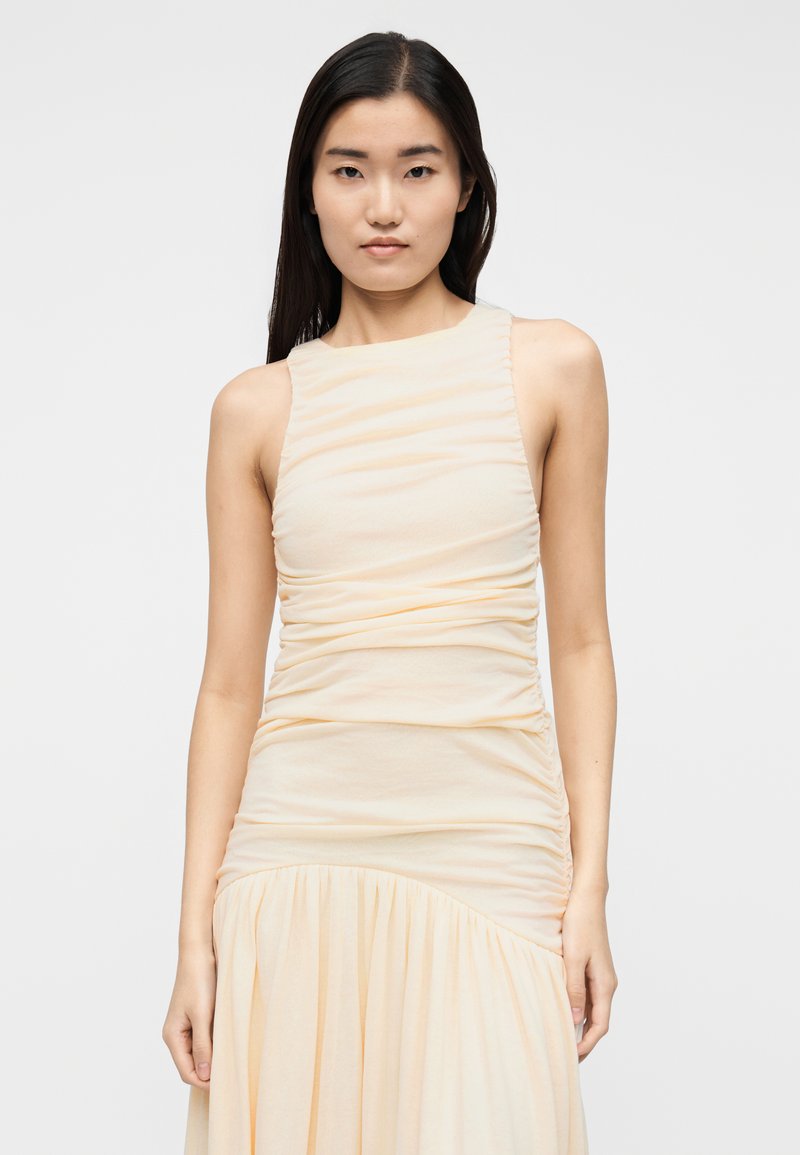 Robe jaune pâle avec un corsage ajusté et des détails froncés ; la jupe s'évase avec de douces plis. Design sans manches avec un col rond.