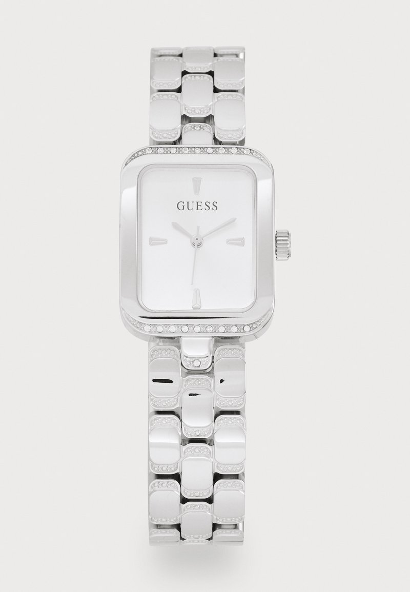 Montre-bracelet Guess argentée avec cadran rectangulaire, index horaires minimalistes et bracelet en métal décoré de petits cristaux incrustés.