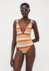 Striped one-piece swimsuit featuring alternating orange, blue, and brown bands. Deep V-neck design, wide straps, and ribbed texture.