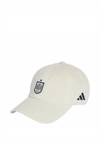 Biała czapka baseballowa z ciemnoniebieskim emblematem z koroną i tarczą oraz ciemnoniebieskimi paskami Adidas po bokach. Wykonana z bawełny.
