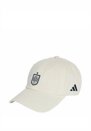 Biała czapka baseballowa z ciemnoniebieskim emblematem z koroną i tarczą oraz ciemnoniebieskimi paskami Adidas po bokach. Wykonana z bawełny.