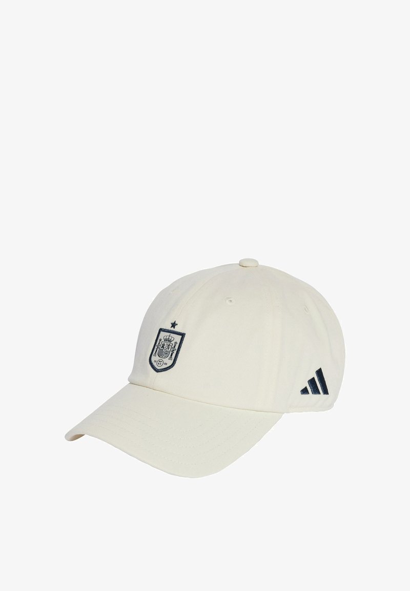 Biała czapka baseballowa z ciemnoniebieskim emblematem z koroną i tarczą oraz ciemnoniebieskimi paskami Adidas po bokach. Wykonana z bawełny.