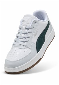 Zapatilla blanca de cuero con acento verde a lo largo del costado, suela de goma, puntera redonda y detalles perforados en la caja de los dedos y la parte superior.