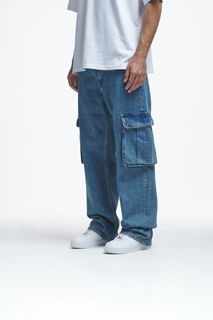 Siniset denim cargo-housut, joissa on useita taskuja, rento istuvuus ja hieman haalistunut pinta; yhdistetty valkoisiin tennareihin ja löysään valkoiseen t-paitaan.