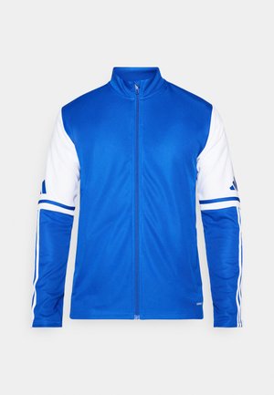 Veste de sport bleue avec fermeture éclair intégrale, col haut, manches blanches et trois bandes blanches sur les épaules. Fabriquée en tissu lisse et léger.