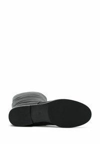 Botte grise à tige en tissu texturé, à bout rond et semelle en caoutchouc noir plat. Pas de matériel ou de motifs visibles.