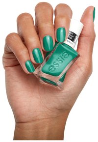 Groene Essie nagellak vastgehouden in een hand, die glanzende, gemiddeld lange nagels toont. De fles heeft een vierkante basis en een cilindrische witte dop.