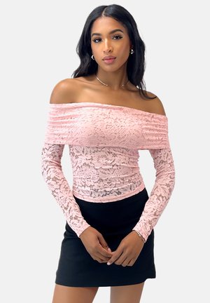 Roze kant off-shoulder top met lange mouwen en een fitted silhouet, gecombineerd met een zwarte mini rok. Bloemenpatroon door het hele kant.